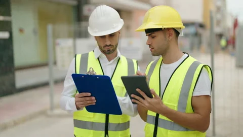 Two hispanic men architects reading document using touchpad at street Video stock 233402047