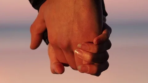 Two Holding Hands of a guy and a girl in sunset rays 1 Stock Footage 77467283