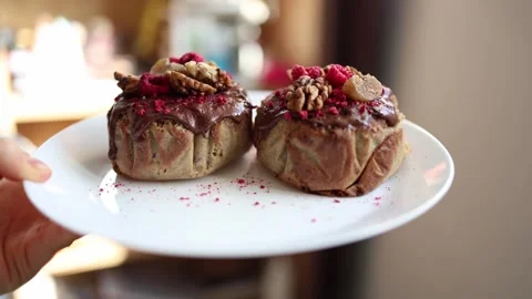 Two homemade Easter cakes decorated with chocolate glaze, walnuts, and dried ras Stock Footage 305295083