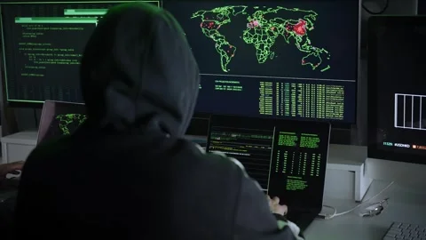 Two hooded hackers working together and pointing at display screens in a Stock Footage 246714454