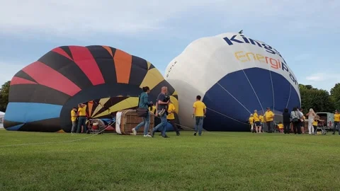 Two hot air balloons lying down in green fields of angera Video stock 280891429