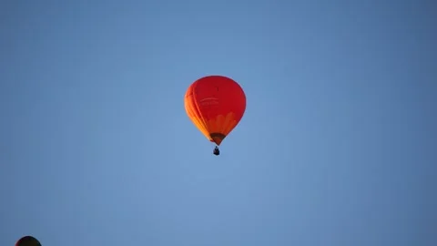 Two hot air balloons soaring in blue sky above rooftop of residential building Stock Footage 318279740