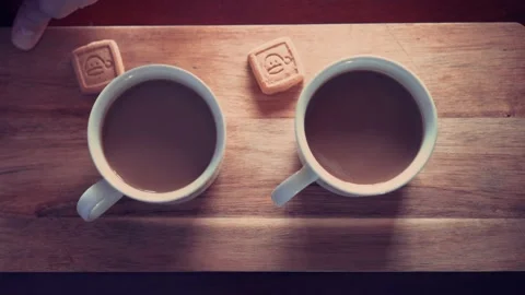 Two hot lattes are served in two cups on a wooden table with two cookies 스톡 동영상 130867069
