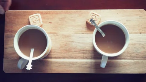 Two hot lattes are served in two cups on a wooden table with two cookies 스톡 동영상 130867090