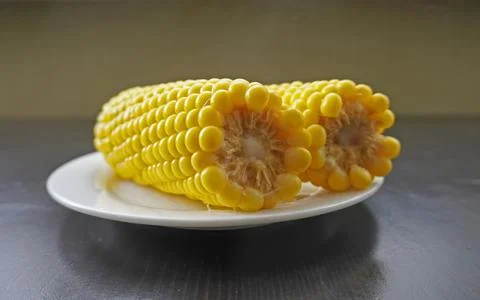 Two hot yellow corn cobs on white plate with steam on dark table, organic s.. Stock Photos