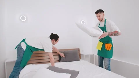 Two hotel staff members making a bed in a modern, minimalist room during Stock Footage 305277045