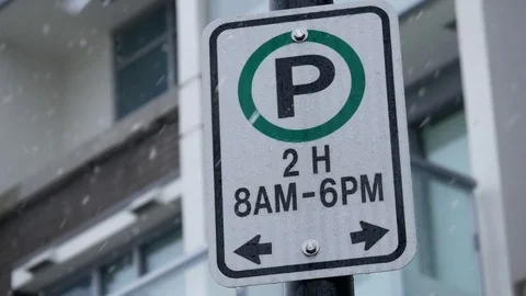 Two hours parking sign in front of new buiding cold blizzard snow winter day 스톡 동영상 73342364