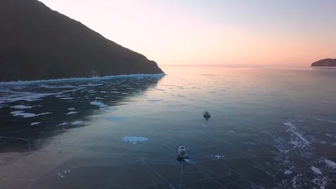 Two hovercraft ride on the ice of Lake Baikal at dawn Stock Footage 123126379