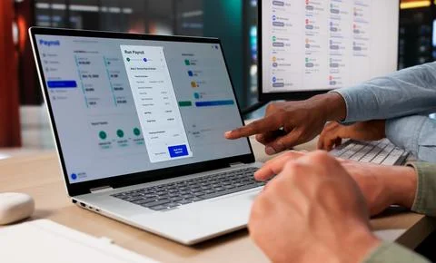 Two HR Managers Using Payroll Software On Laptop To Calculate Employee Salari Stock Photos