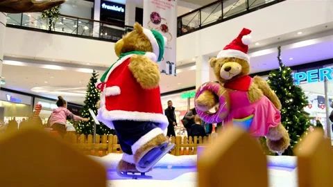 Two huge artificial bear dolls dressed in Santa costumes are skating. Stock Footage 134967349