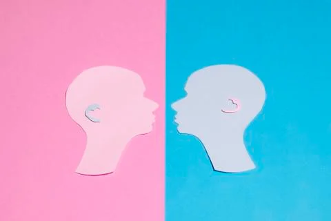 Two human profiles cut out of paper on a pink-blue background Stock Photos