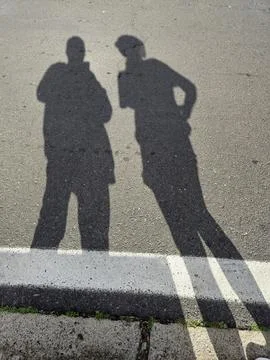 Two Human Shadows on Sunlit Asphalt Road Stock Photos