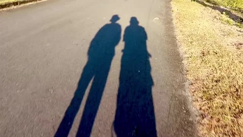 Two human shadows walking along a path at sunset Stock Footage 326776157