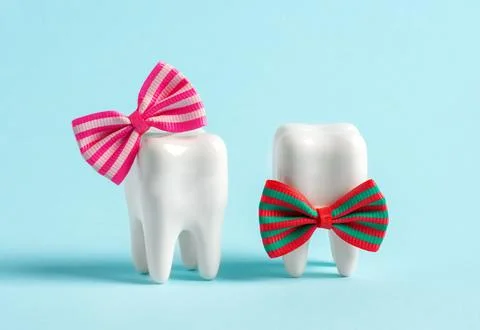 Two human teeth wearing cute bows on blue background. Stomatology clinic po.. Stock Photos