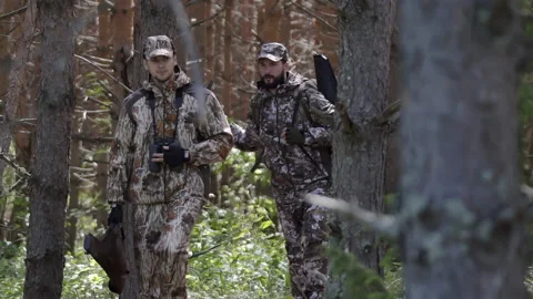 Two hunter men in camouflage clothes with guns walking through forest during 스톡 동영상 133245482