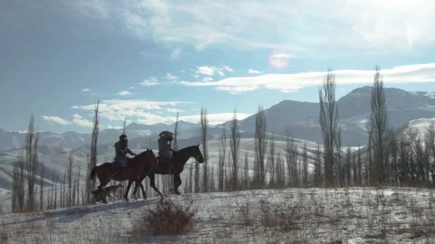 Two hunters with golden eagles on their arms ride a horses. Hunting dogs. Winter Stock Footage