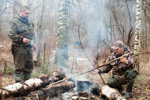 Two hunters over the campfire Stock Photos