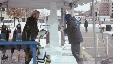 Two Ice carvers making ice sculpture at winter festival in Carmel Indiana Stock Footage 153439828