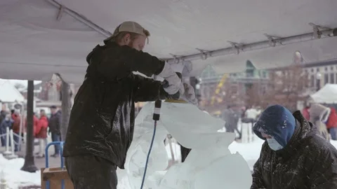 Two Ice carvers making ice sculpture at winter festival in Carmel Indiana Stock Footage 153440282