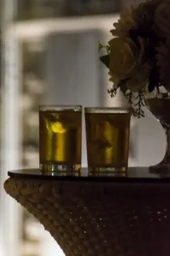Two ice cold drinks standing on table at night in front of windows Stock Photos