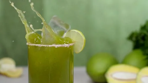 Two ice cubes falling inside a clear glass of refreshing drink, Aam Panna Stock Footage 154395906