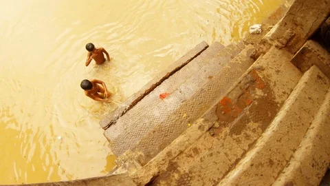 Two indian boys without clothes wash themselves in dirty water of river Ganga be Stock Footage 119531988