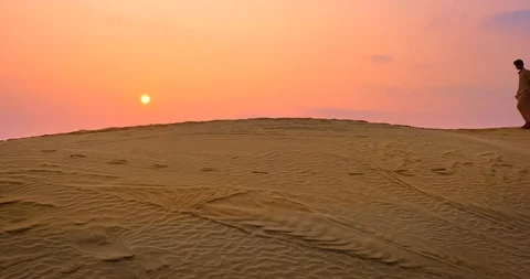 Two Indian cameleers (camel driver) bedouin with camel silhouettes in sand dunes Stock Footage 122948784