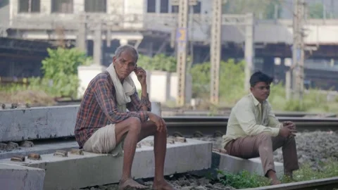 Two Indian men sitting dangerously close to a railway tracks Video stock 335460042