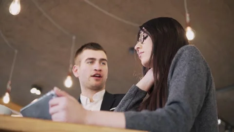 Two individuals are seen collaborating in a cozy cafe setting, engaged in dis Stock Footage 335602652