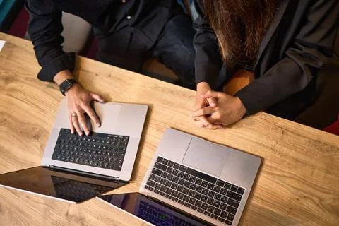Two individuals collaborating on laptops in a stylish office setting during a Stock Photos