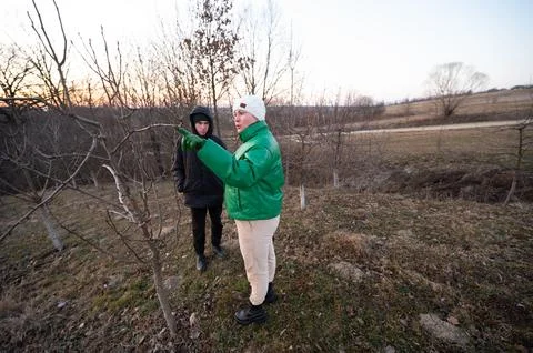Two individuals engage in conversation about tree care in a serene rural area Stock Photos