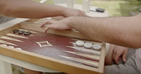 Two individuals enjoying a game of backgammon outdoors on a sunny day with Stock Footage 281578819