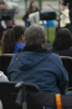 Two individuals seated side by side watching performance outdoors Fotos Stock