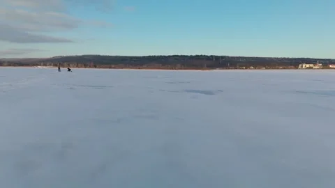 Two individuals walking on a frozen lake with snow-covered surface and distant Vídeo Stock 331755152