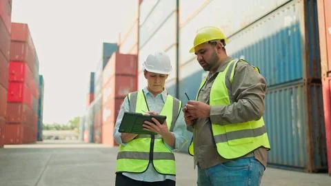 Two industrial engineer using tablet working together at the container warehouse Foto stock