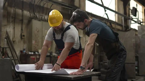 Two industrial workers analyzing blueprint in a factory Stock Footage 334723141