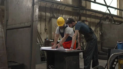 Two industrial workers analyzing blueprint in a factory Video stock 334723198