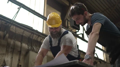 Two industrial workers discussing project blueprints in a factory Stock-Footage 334723134