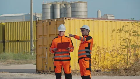 Two Industrial Workers in Orange Safety Uniforms Checking and Consulting wi.. 動画素材 337726558