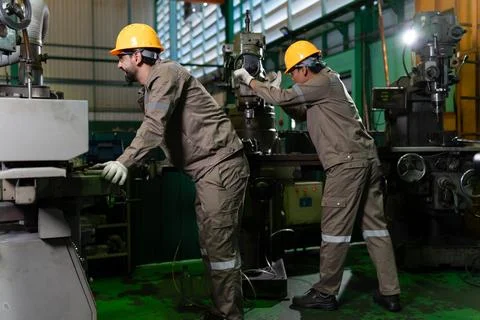 Two industrial workers wearing hard hats and protective clothing operate mi.. Stock Photos