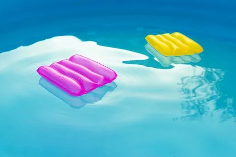Two inflatable pillows lie on the surface of the water in the pool Stock Photos