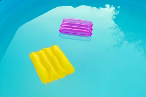 Two inflatable pillows lie on the surface of the water in the pool Stock Photos