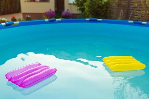 Two inflatable pillows lie on the surface of the water in the pool Stock Photos