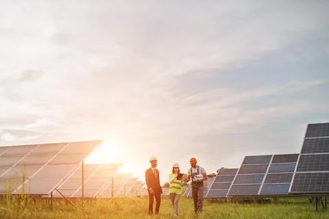 Two inspectors talking with technician at solar station Stock Photos