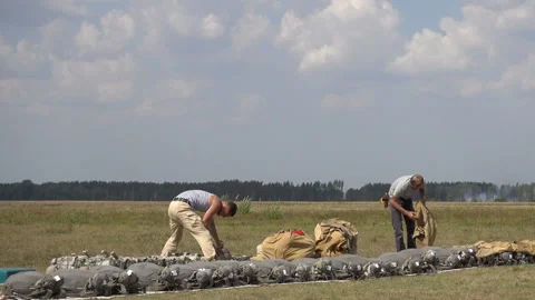 Two instructors of parachuting are engaged on the field by assembling parachute Stock Footage 95293002