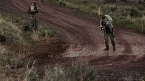 Two instructors placing a training explosive on the side of a dirt road. Stock Footage 52703657
