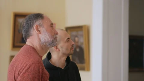 Two intelligent men in the Museum look at the exhibit, and talk about art Stock Footage 128470663