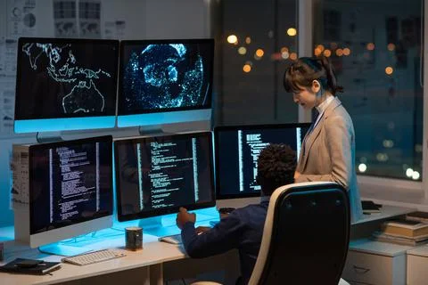Two intercultural programmers decoding data on computer screen Stock-Fotos