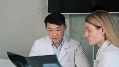 Two International Doctors Talk Working, Analysing Patient X-ray Patient's Lungs. Video stock 234182184