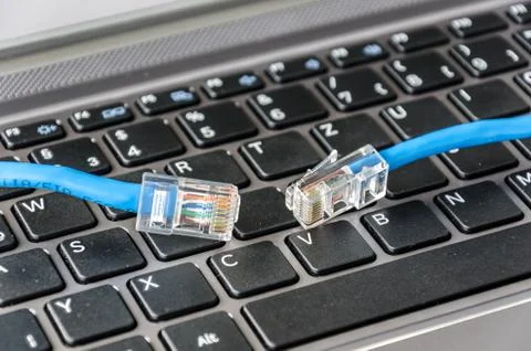 Two internet cables on a computer keyboard symbolizing connectivity issues Stock Photos